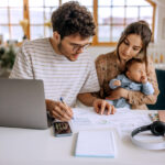 Young family with cute little baby boy going over finances at home